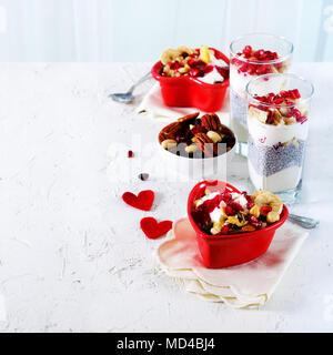 Petit-déjeuner romantique avec chia, granola, yogourt et fruits rouges sur fond de béton blanc. Santé et alimentation concept Banque D'Images