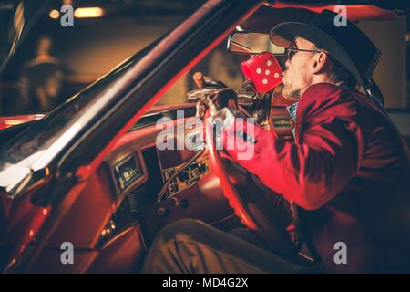 Lucky Casino Winner rouge baiser dés Craps à l'intérieur de sa voiture classique. Les hommes de race blanche dans la trentaine portant Bourgogne Suite et chapeau de cowboy. Banque D'Images