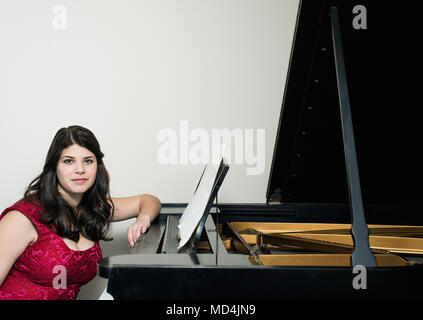 Une femme assise à un piano à queue. Banque D'Images