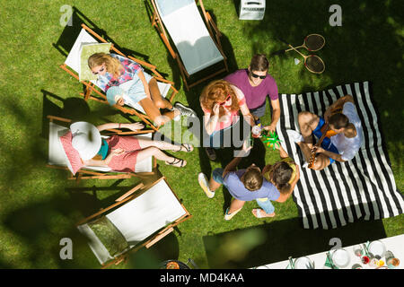 Vue de dessus du groupe d'amis appréciant summertime garden party à la campagne, assis sur des chaises, à parler et à bronzer entouré par la nature Banque D'Images