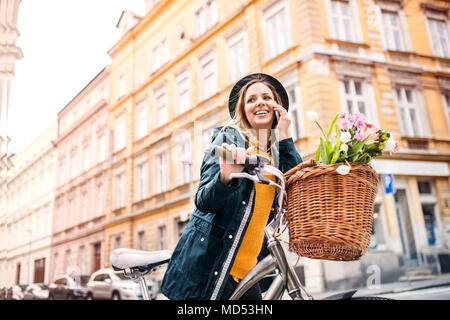 Jeune femme avec location et smartphone sous le soleil de printemps la ville. Banque D'Images