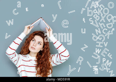 Étudiant sérieux tenant un ordinateur portable et à la fatigue de l'apprentissage des langues Banque D'Images