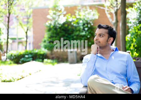 Closeup portrait, souriant, joyeux, heureux jeune homme d'affaires, là, à rêver de belles choses, à l'extérieur, arbres isolés sunny arrière-plan. Hum Positive Banque D'Images