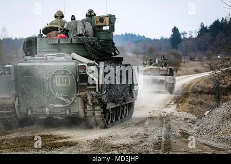 Un véhicule de combat Bradley M2 pistes a M1 Abrams tank, tous deux de la 5e Escadron, 4e régiment de cavalerie blindée, 2e Brigade Combat Team, 1re Division d'infanterie, tout en se déplaçant pour sécuriser une zone au cours d'un exercice de tir réel interarmes (CALFEX) au secteur d'entraînement Grafenwoehr, Allemagne, Mar 26, 2018. (U.S. Photo de l'armée par la CPS. Hubert D. Delany III / 22e Détachement des affaires publiques mobiles) Banque D'Images