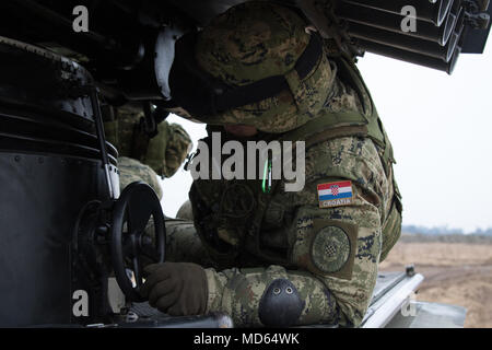 Un soldat de l'artillerie croate affecté à l'aide de la batterie du volcan dans la mise en place de son équipe Vulkan M-92, les lance-roquettes multiples, où ils se préparent à fournir l'appui feu tout en participant à la 3e Escadron, 2e régiment de cavalerie, à l'exercice de tir réel de l'escadron une gamme près de la zone d'entraînement Bemowo Piskie, Pologne, le 23 mars 2018. Ces soldats sont une partie de l'unique groupe de combat multinationales, composé de États-Unis, Royaume-Uni, croate et soldats roumains qui servent avec la 15e Brigade mécanisée polonaise comme une force de dissuasion dans le nord-est de la Pologne à l'appui de l'OTAN est une présence avancée Banque D'Images