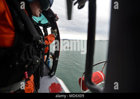 Un mécanicien de vol à bord d'un hélicoptère MH-65 de Dolphin Coast Guard Air Station Humboldt Bay à Eureka, Californie, se prépare à baisser une nacelle de sauvetage d'une embarcation à moteur de 47 pieds au cours de la formation de l'équipage, le 7 mars 2018. Les équipages des hélicoptères de la Garde côtière canadienne effectuent couramment des équipages de petits bateaux avec formation de maintenir leurs qualifications et ainsi que dans le cas d'une évacuation sanitaire demande d'un bateau ou navire, les équipages sont compétents dans leurs techniques de sauvetage. Banque D'Images