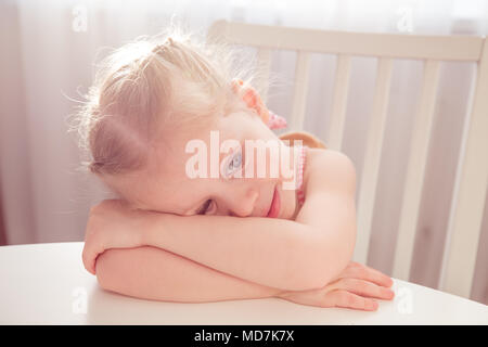 Fille de rêve à la table. Petite fille heureuse à la maison. Banque D'Images