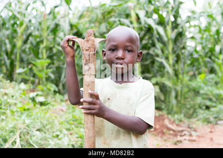 L'Ouganda. 17 juin 2017. Un petit garçon ougandais tenant une houe. Banque D'Images