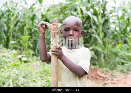 L'Ouganda. 17 juin 2017. Un petit garçon ougandais tenant une houe. Banque D'Images