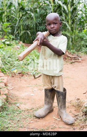 L'Ouganda. 17 juin 2017. Un petit garçon ougandais tenant une houe. Banque D'Images