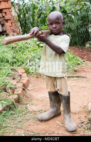 L'Ouganda. 17 juin 2017. Un petit garçon ougandais tenant une houe. Banque D'Images