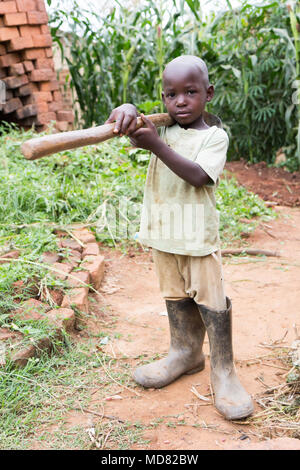 L'Ouganda. 17 juin 2017. Un petit garçon ougandais tenant une houe. Banque D'Images