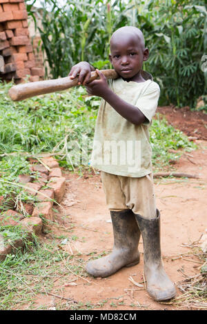 L'Ouganda. 17 juin 2017. Un petit garçon ougandais tenant une houe. Banque D'Images