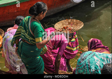 Les femmes portent des paniers contenant des fleurs et d'encens comme offrande à la Ganges Banque D'Images