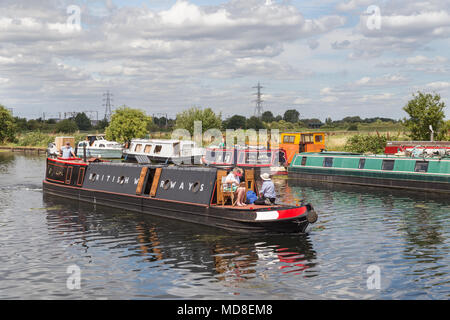 Le bateau à Narrowboat avec des occupants d'âge moyen se déplaçant le long de la rivière Lea dans le nord de Londres, pendant une journée d'été ensoleillée Banque D'Images