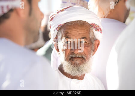 Nizwa, Oman - Mar 23, 2018 : Portrait d'un vieil homme omanais parmi d'autres hommes participant à une vente aux enchères le chèvre une chèvre tôt vendredi matin, marché. Banque D'Images