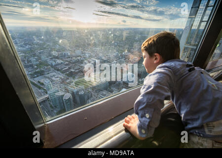 Boy admiring Toronto cityscape à partir de la fenêtre de verre, Canada Banque D'Images