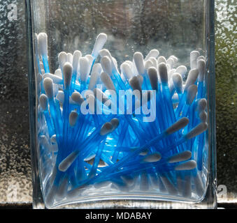 Close up d'oreillettes tige en plastique dans un bocal de verre dans une salle de bains intérieure Banque D'Images