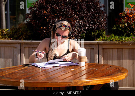 Tayside, Dundee, Ecosse, Royaume-Uni. 19 avril, 2018. Météo France : Sex Spanish Plume déferle sur l'Amérique du Nord Est de l'Écosse avec des températures qui atteignent 20 °C ; devenir le printemps le plus chaud depuis des décennies. Un jeune élève assis à étudier tout en écoutant de la musique à partir de son téléphone mobile à la place d'une table de pique-nique sur une chaude journée ensoleillée d'avril à Dundee. UK. Credit : Dundee Photographics / Alamy Live News Banque D'Images