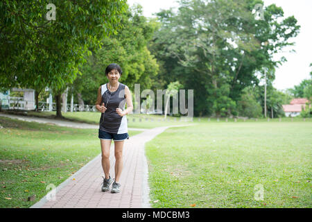 Vue avant du senior woman jogging through park Banque D'Images