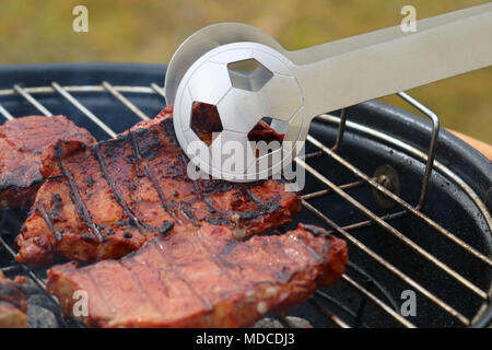 Close up de savoureux steaks sur le gril du barbecue avec la Coupe du Monde de Football tong Banque D'Images