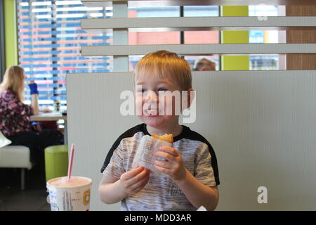 Un petit garçon, le petit-déjeuner à Mc Donald's à Llandudno Banque D'Images