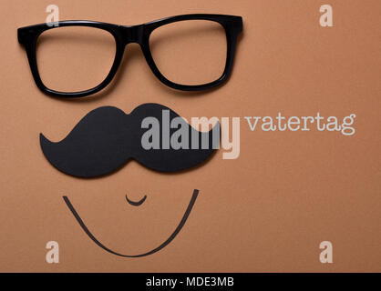 Une paire de lunettes et une moustache formant la face d'un homme sur un fond brun et le texte vatertag, pères jour écrit en allemand Banque D'Images