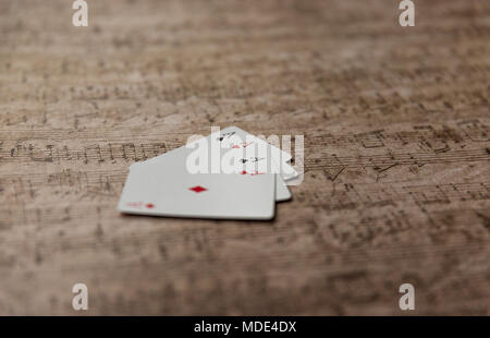 Carte à jouer quatre as empilés sur une vieille feuille de musique. Banque D'Images