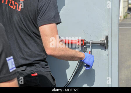 Fire fighter utilise les outils hydrauliques à enfreindre une porte verrouillée Banque D'Images