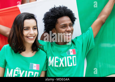 Deux cheering fans de foot à partir du Mexique, au stade avec drapeau mexicain Banque D'Images