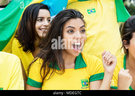 Femme du Brésil regarder jeu avec d'autres fans de football brésilien à stade Banque D'Images