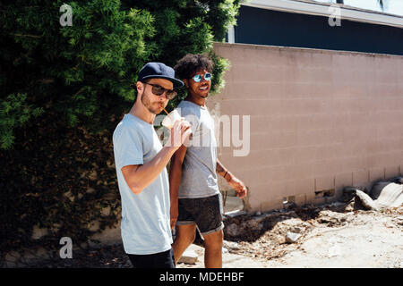 Les amis marchant sur un chemin de terre par wall Banque D'Images