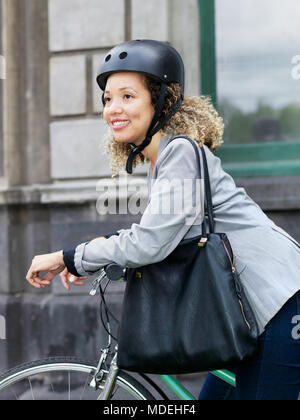 Mid adult woman sitting on bicycle, le port de casque de sécurité Banque D'Images