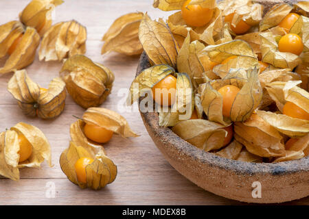 Physalis peruviana. Physalis les fruits dans un bol sur une planche en bois Banque D'Images