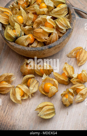 Physalis peruviana. Physalis les fruits dans un bol sur une planche en bois Banque D'Images