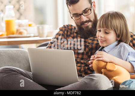 Smiling père et fils de regarder un film ensemble, assis sur un canapé Banque D'Images