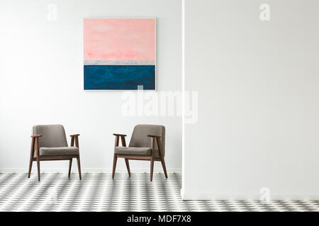 Peinture pastel sur mur blanc au-dessus des fauteuils gris en intérieur avec sol en damier Banque D'Images