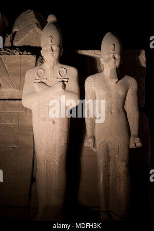 Hauteur de l'Égypte ancienne en pierre de statues dans le Temple de Karnak à Louxor illuminé durant la nuit sur fond de ciel noir Banque D'Images