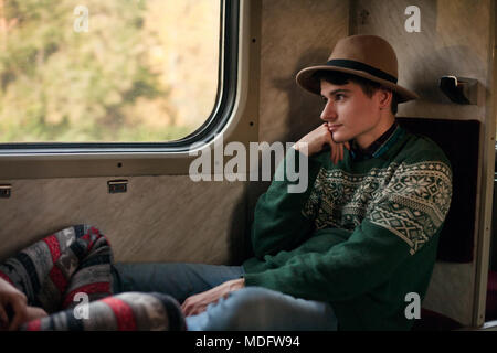 Jeune homme assis dans un train Banque D'Images