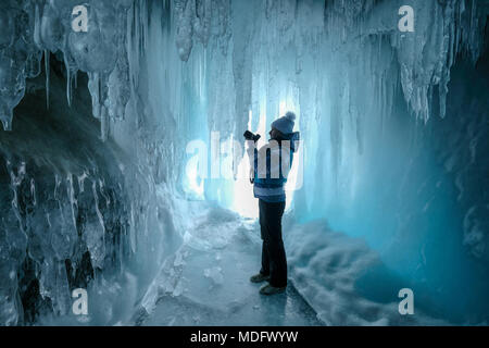 Femme debout dans une grotte de glace prenant une photo, Oblast d'Irkoutsk, Sibérie, Russie