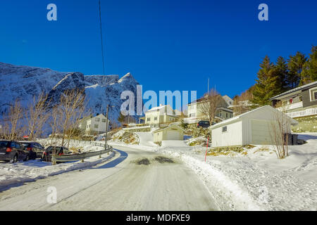 Henningsvær, Norvège - le 04 avril 2018 : vue extérieure de maisons en bois à un côté de la route couverte de neige d'un petit village typique dans les îles Lofoten Banque D'Images