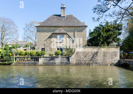 Jolie maison en pierre de Cotswold à côté de la rivière Windrush dans le populaire village de Cotswold Bourton-on-the-water, Gloucestershire dans soleil du printemps Banque D'Images