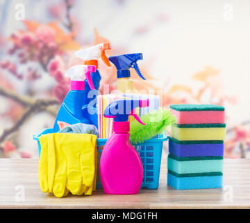 Nettoyage de printemps - concept et de caoutchouc coloré bouteilles sprays sur table en bois sur fond d'arbres en fleurs de printemps Banque D'Images