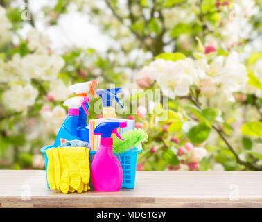 Nettoyage de printemps - concept et de caoutchouc coloré bouteilles sprays sur table en bois sur fond de printemps de fleurs de pommier Banque D'Images