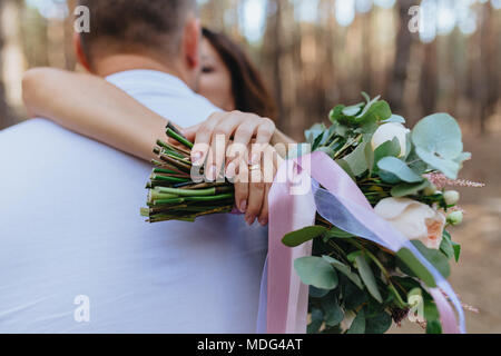 La femme et l'homme dans la forêt. Bride hugs mari. Bride holding a bouquet de fleurs. L'amour. Banque D'Images