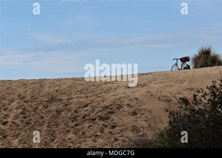 Un vélo est garé sur les dunes de sable - peut-être pour un pique-nique, et le surf dans l'Atlantique près de l'Amelie, Gironde Banque D'Images