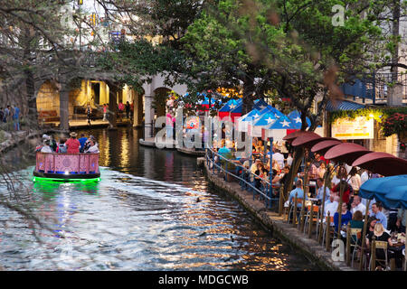 San Antonio River Walk - - un bateau de tourisme sur la rivière San Antonio passant restaurants au crépuscule ; le San Antonio Riverwalk, San Antonio Texas USA Banque D'Images