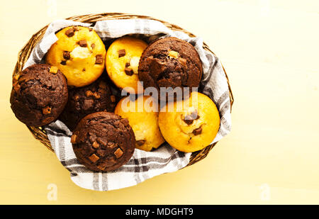 Une sélection de muffins dans panier en osier jaune sur surface de travail, tourné de haut en bas Banque D'Images