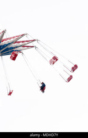 Situé à Luna Park de Coney Island à Brooklyn New York sous couvert ciel blanc brillant, swing ride avec seulement deux personnes sur le siège. Banque D'Images