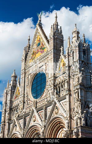 Close-up of decorative and ornate façade de la Cathédrale de Sienne avec ciel bleu et nuages ; Sienne, Toscane, Italie Banque D'Images